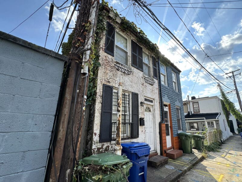 Angled front view of 2337 Duker Court showing ivy-covered brick wall and alley access.