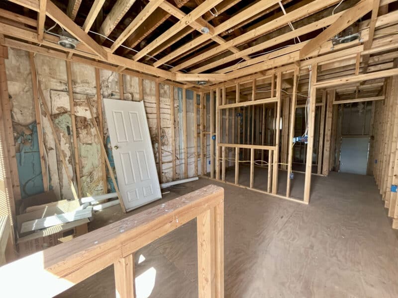 Framed interior with construction materials and detached door leaning on framing.