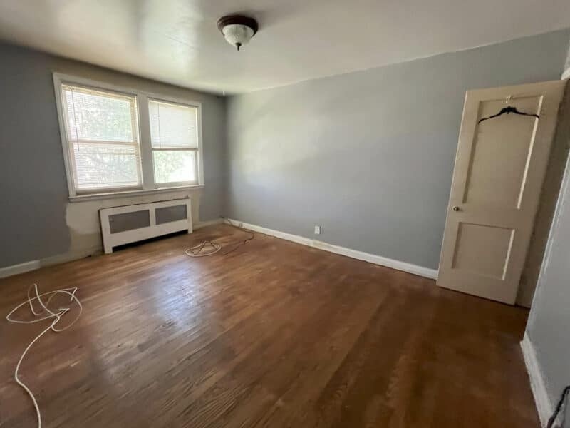 Third bedroom with hardwood floors, gray-painted walls, and front-facing windows.
