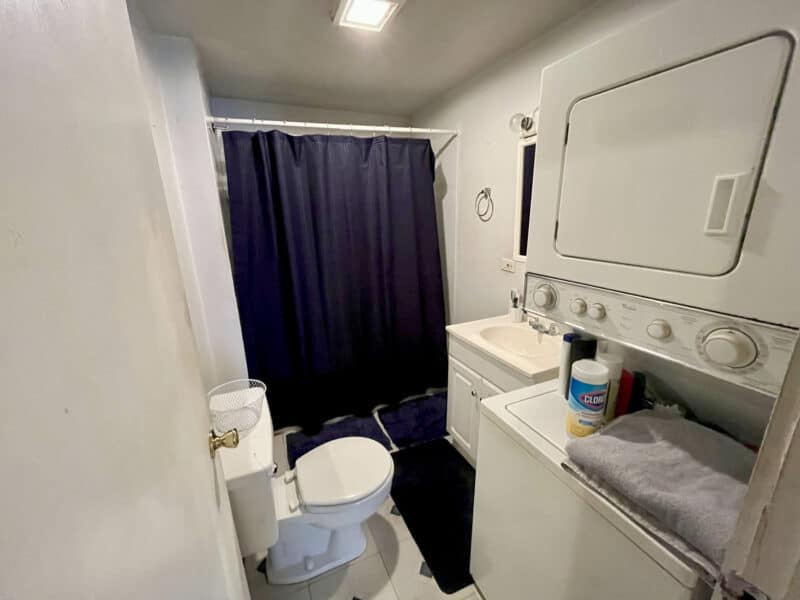 Bathroom with tub/shower combo, toilet, vanity, and stacked washer/dryer