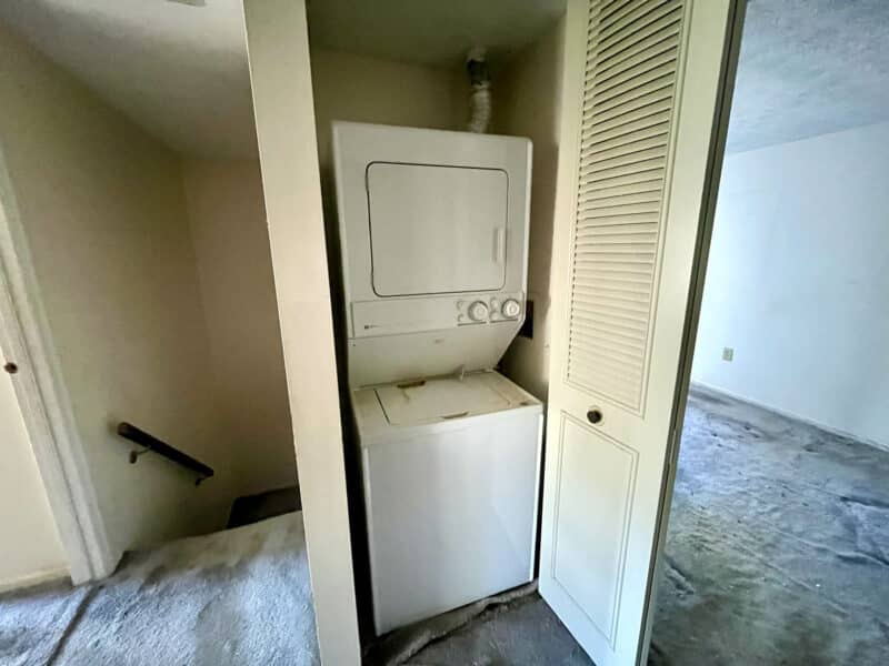 Upper-level laundry closet with stacked washer and dryer unit.