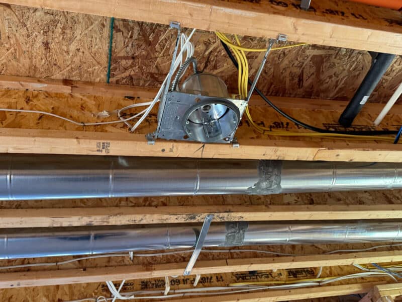 Close-up of electrical rough-in with recessed lighting housing and wiring.