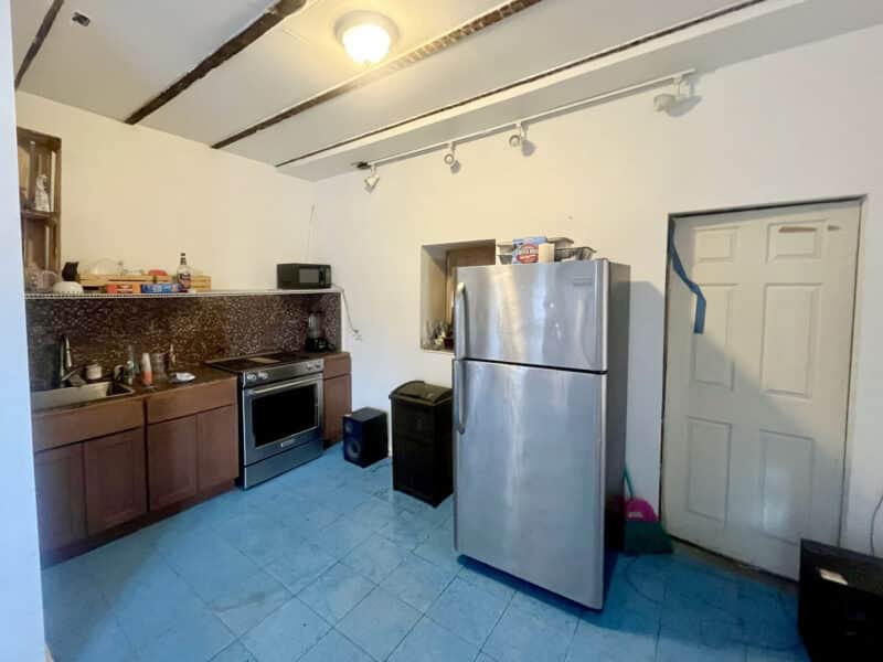 Small kitchen area featuring refrigerator, oven, and wooden cabinetry.