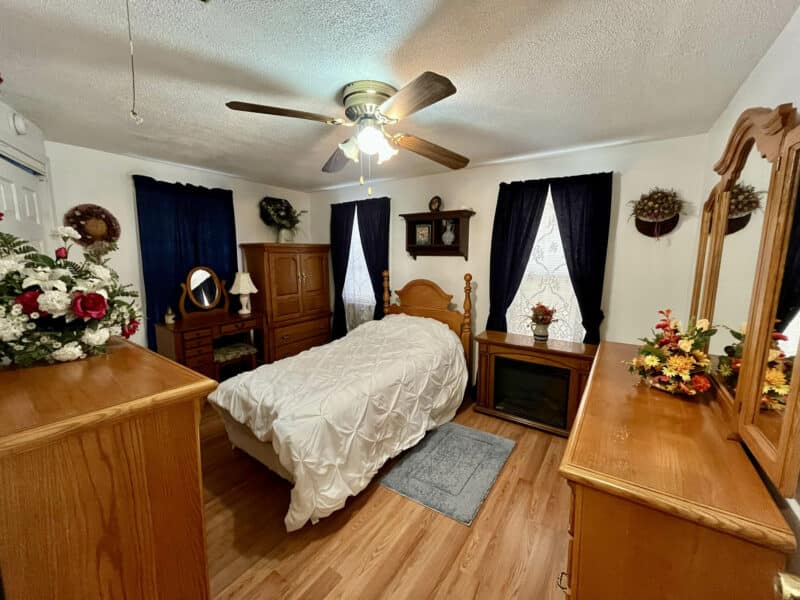 Primary bedroom inside two-story farmhouse at 1207 Joppa Road in Joppa, Maryland, featuring wood floors, ceiling fan, natural light, and traditional décor.