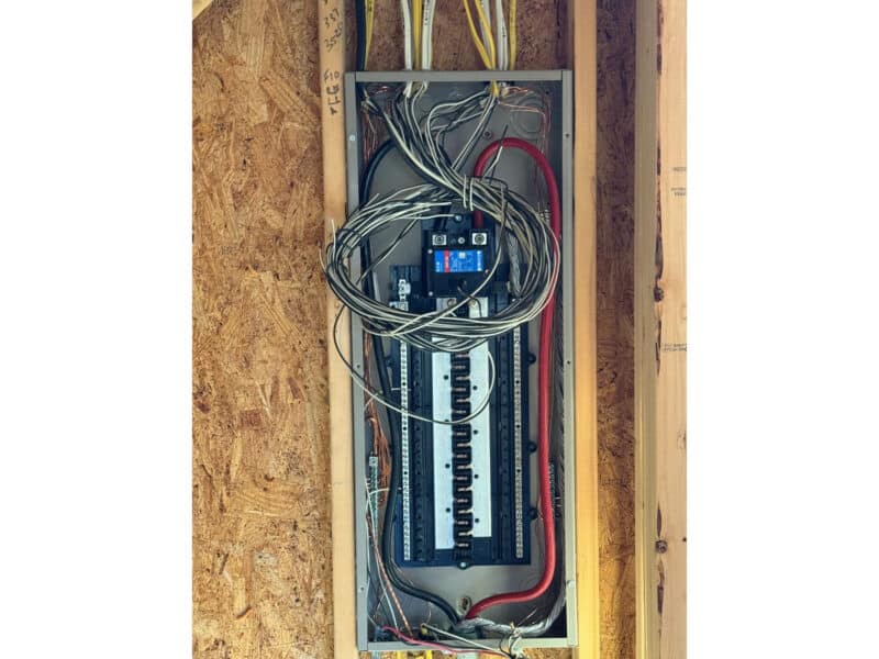 New electrical panel rough-in installed between wall studs with wiring routed.