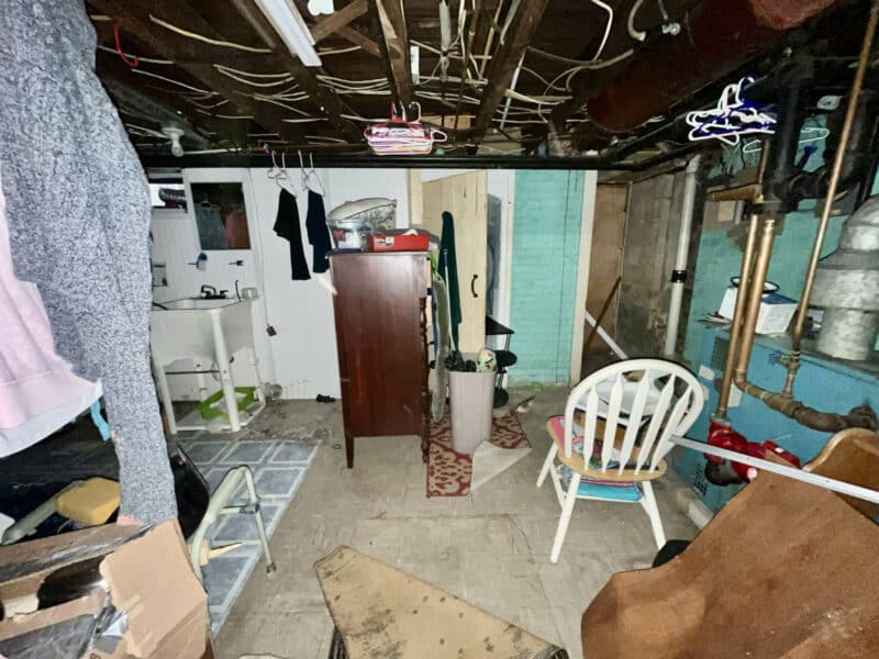 Unfinished basement with open ceiling, concrete floor, and utilities.