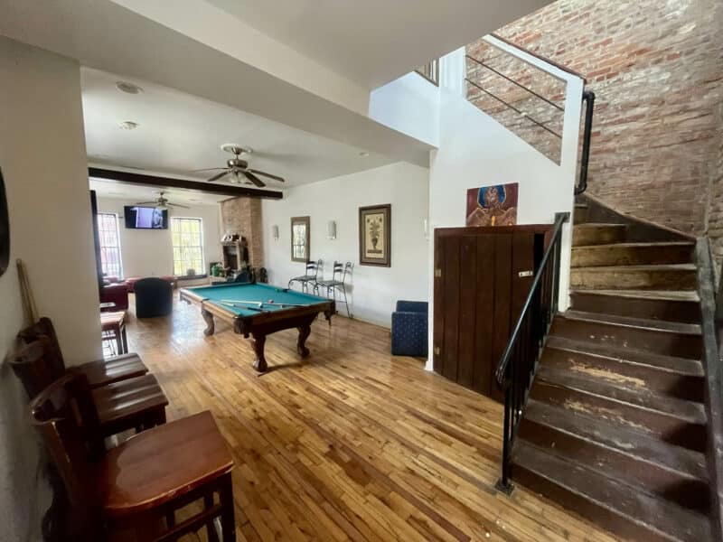Large open room with pool table, wood flooring, and stair access.