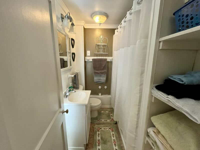 Full bathroom inside 1207 Joppa Road farmhouse in Joppa, MD, with vanity, tub/shower combo, built-in shelving, and neutral finishes.