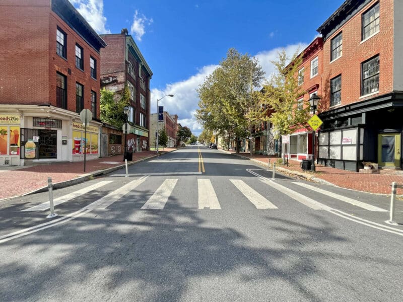 View down Baltimore Street lined with brick storefronts and residential buildings.