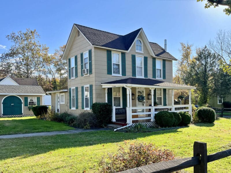 Main exterior view of the two-story farmhouse at 1207 Joppa Road in Joppa, Maryland, showing front elevation, porch, landscaping, and surrounding yard.