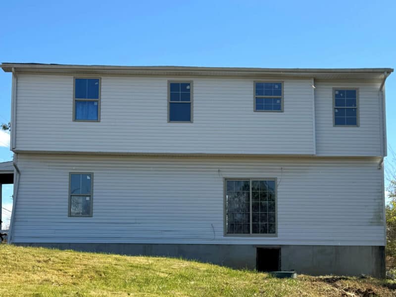 Rear view of two-story home with new siding and walk-out access.