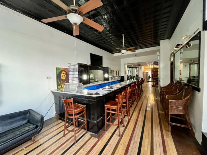 Interior view of bar area featuring counter seating, wood floors, and decorative ceiling.