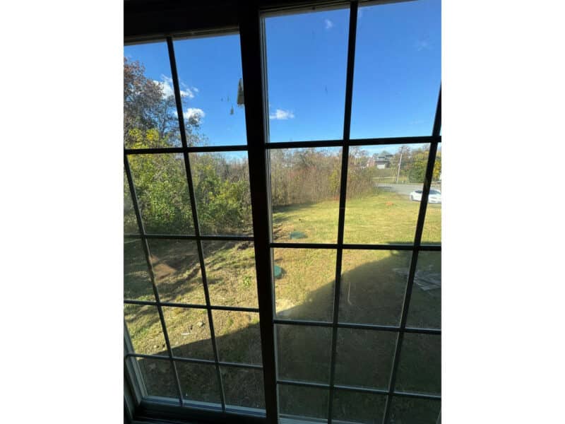 View from second-floor window overlooking open yard and trees.