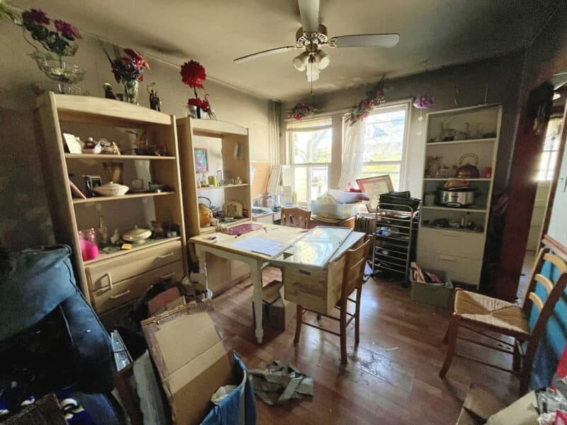 Dining room with clutter, ceiling fan, and front-facing bay windows.