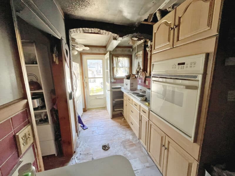 Kitchen with significant fire damage to ceiling and cabinets.