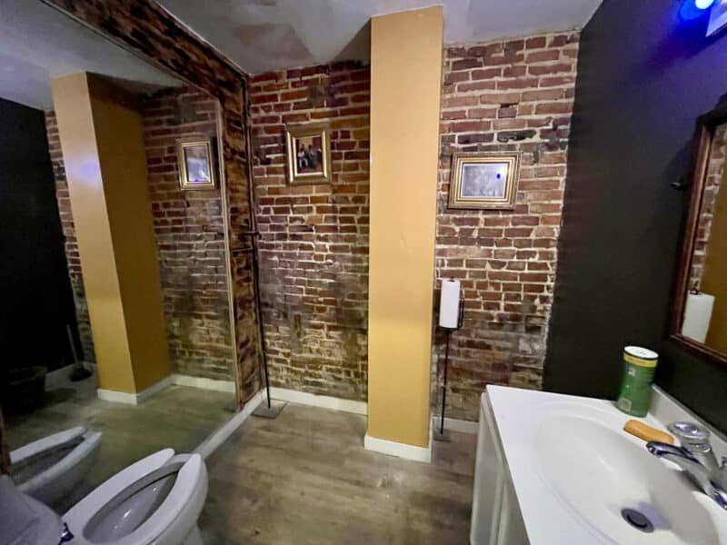 Bathroom featuring exposed brick, modern sink, and bright lighting.