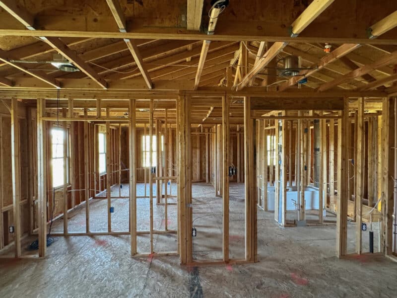 Second-floor framing showing bedroom and bathroom layouts with exposed joists.