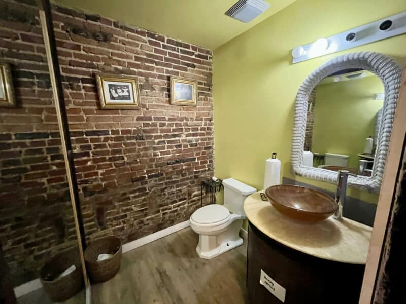 Bathroom with vessel sink, framed mirror, and partial brick accent wall.