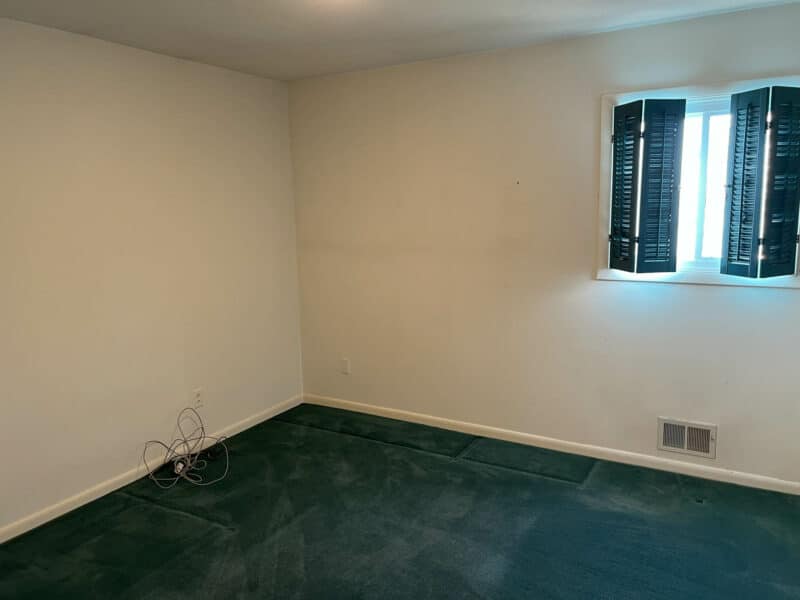Bedroom with green carpet, neutral walls, and shuttered window at 4729 Byron Road.
