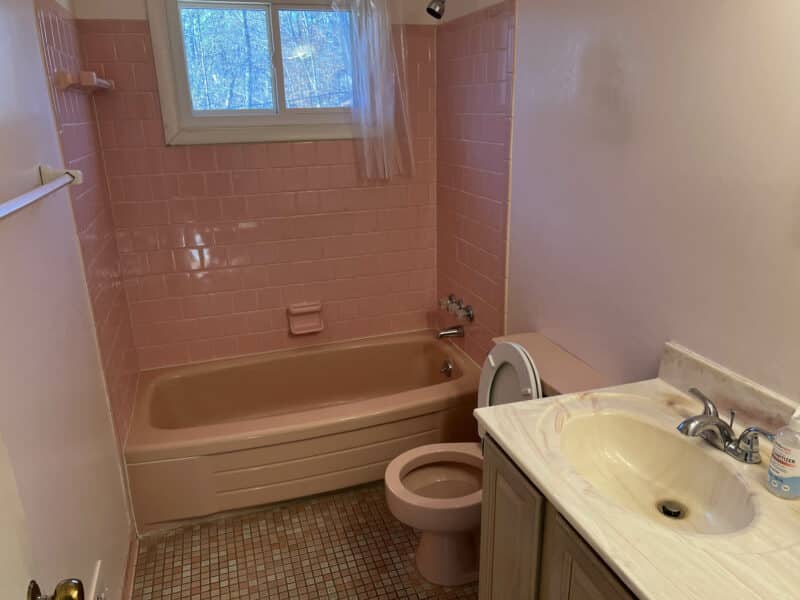 Full bathroom with pink tile tub surround, vintage fixtures, and vanity at 4729 Byron Road.
