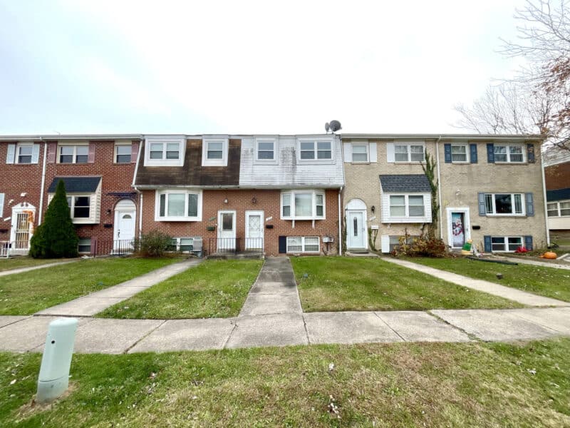 Front view of row of townhomes in Huntsmoor Village North with sidewalks and maintained lawns.