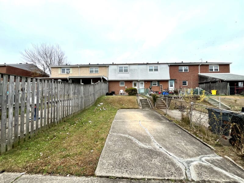 Rear driveway and parking pad behind townhome with fenced yard and access to basement walkout.