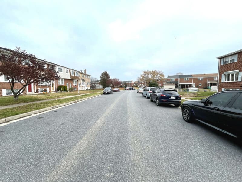 Street view of Stormont Circle in Huntsmoor Village North with brick townhomes and parked cars lining both sides of the road.
