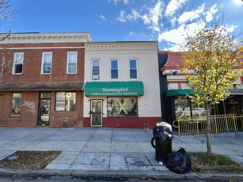 Front exterior of 3217 Belair Road, brick commercial building with green awning for Hummingbird Carryout along Belair Road commercial corridor in Northeast Baltimore.