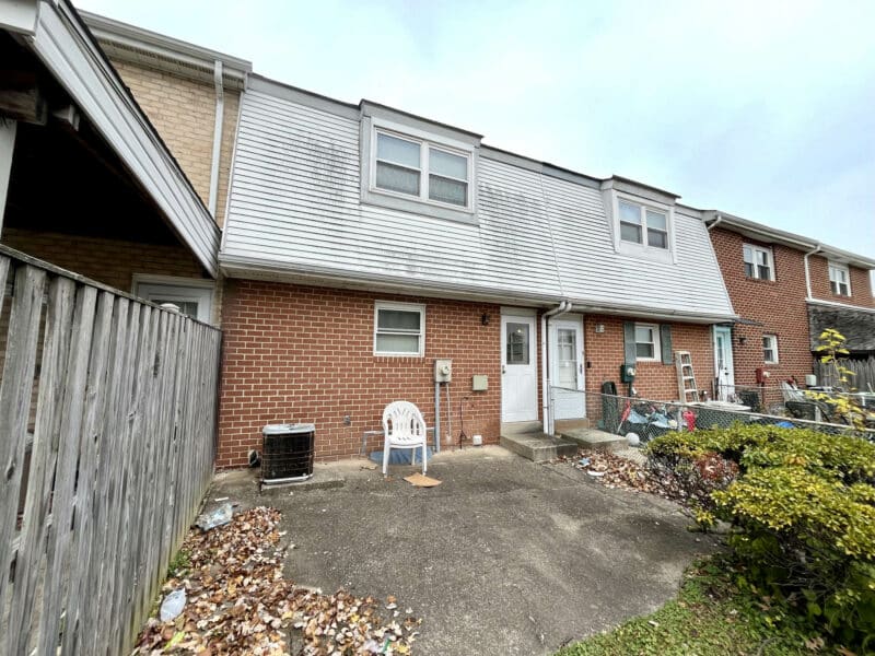 Rear exterior of 1014 Stormont Circle showing paved parking pad and back entrance.
