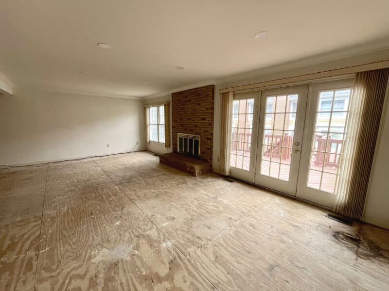 Open living room with brick fireplace, sliding doors, and exposed subfloor ready for new finishes.