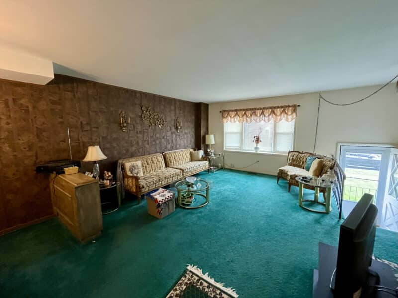 Living room with large front window, green carpet, and paneled wall at 1014 Stormont Circle.