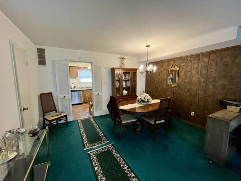 Dining room with wood-paneled accent wall and green carpet at 1014 Stormont Circle.