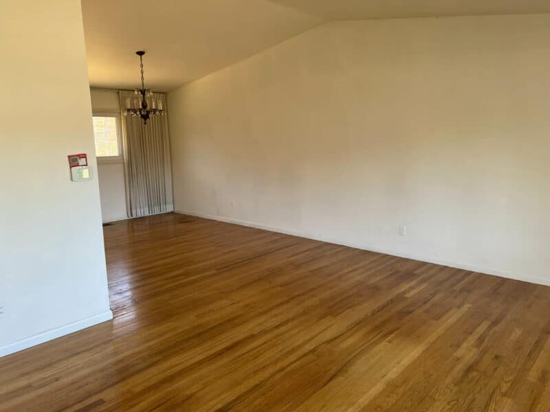 Bright living and dining room at 4729 Byron Road with hardwood floors, cathedral ceiling, and large picture windows.