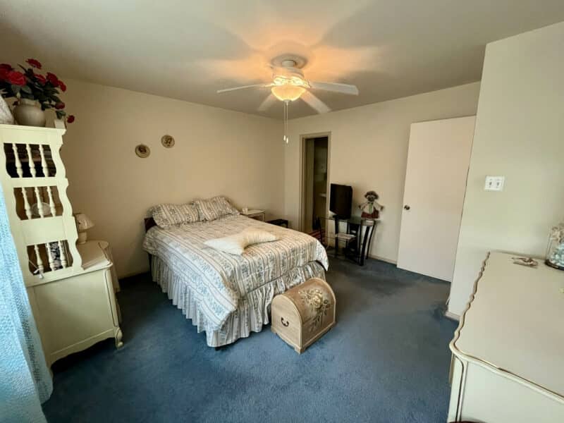 Primary bedroom with blue carpet, ceiling fan, and ample floor space at 1014 Stormont Circle.