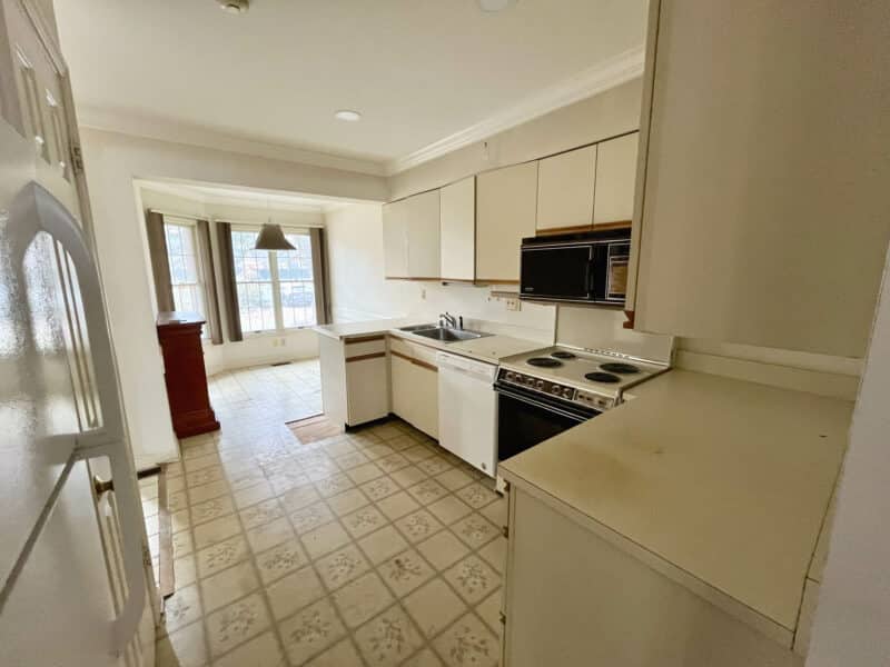 Full kitchen view with extensive white cabinets, double sink, dishwasher, and patterned tile flooring.
