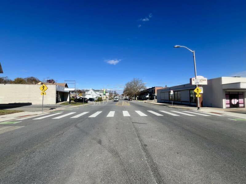 Street-level view of crosswalk and surrounding retail district near 6826–28 Harford Road.