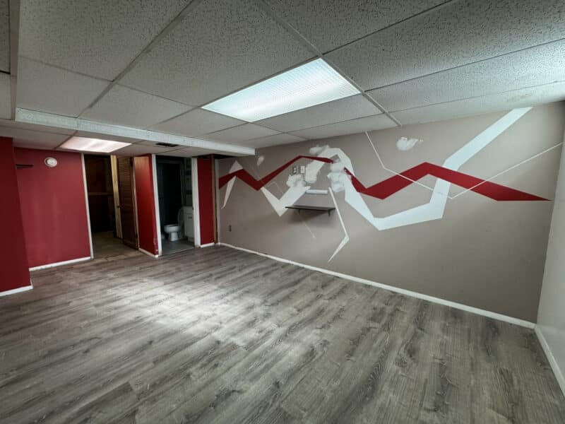 Finished basement at 2808 Windsor Avenue featuring wood-look vinyl floors, recessed lighting, and a red and white geometric accent wall.