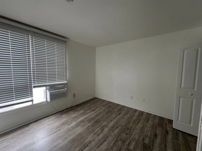 Bedroom with large window, blinds, wood-style flooring, and new lighting.