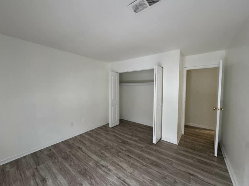 Bedroom with double door closet, wood-style floors, and neutral paint.