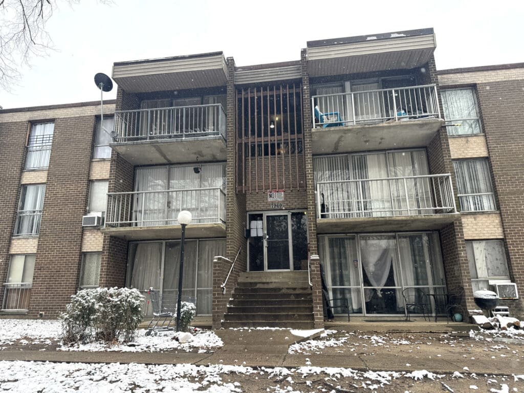 Exterior view of The Marylander condominium building on Riggs Road in Hyattsville, MD, showing brick façade, balconies, and snow-covered landscaping.