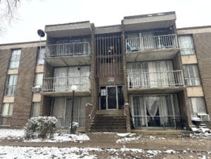 Exterior view of The Marylander condominium building on Riggs Road in Hyattsville, MD, showing brick façade, balconies, and snow-covered landscaping.