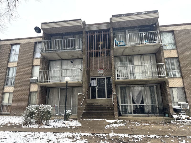 Exterior view of The Marylander condominium building on Riggs Road in Hyattsville, MD, showing brick façade, balconies, and snow-covered landscaping.