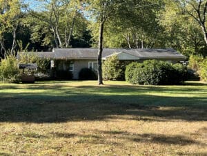 Front exterior view of the vinyl-sided rancher at 1129 Thompson Avenue in Severn, Maryland, set on a large 5.2± acre wooded lot.
