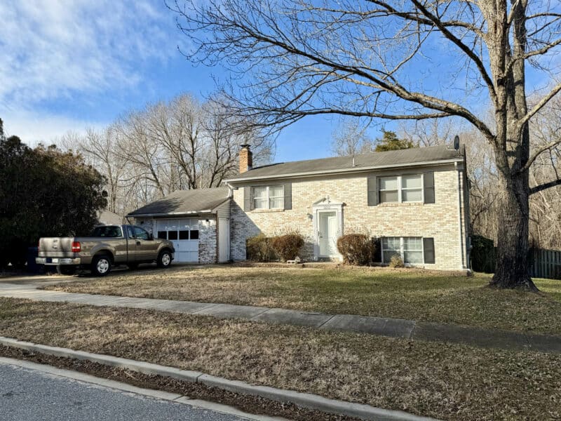 Angled front exterior view of split-foyer home at 10201 Le Fevre Drive in Cheltenham, MD, with mature trees and residential setting.