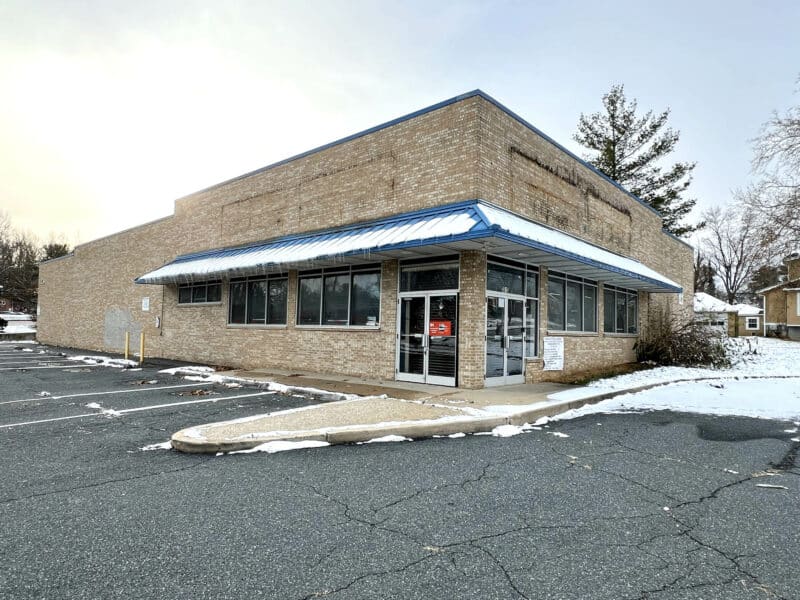 Front exterior of retail building at 3615 E. Northern Parkway with paved parking lot and storefront entrance.