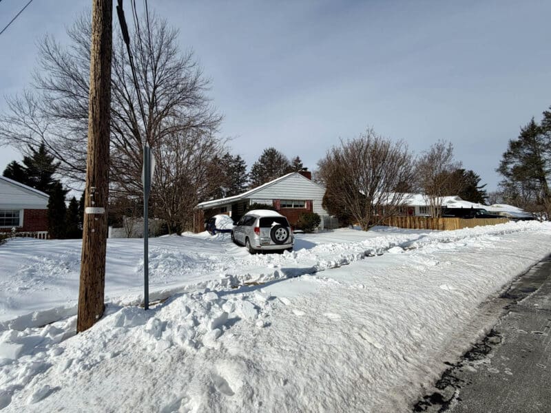 Wide street view of 7404 Knollwood Road rancher with driveway and carport in Towson MD