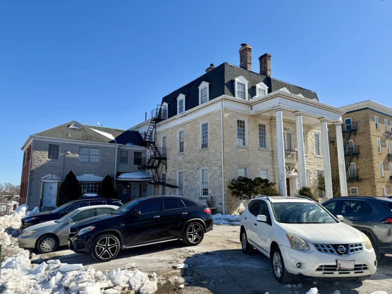 Parking lot view of McCabe Mansion with rear building access and adjacent structures