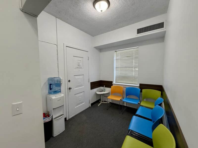 Waiting room with colorful chairs and water dispenser inside McCabe Mansion commercial building