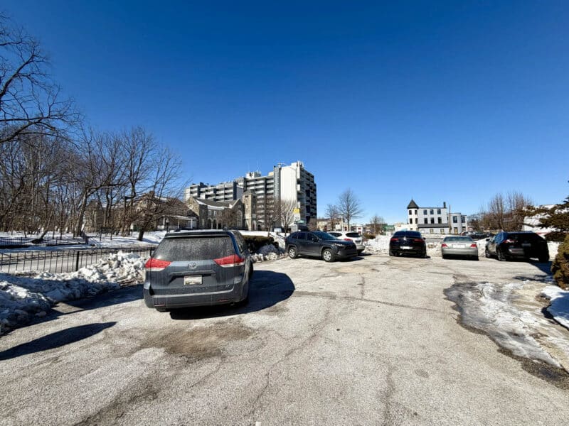 Front parking lot of McCabe Mansion with nearby apartment buildings in background
