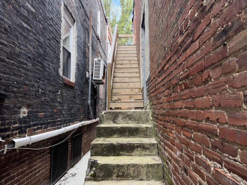 Rear exterior access with concrete stairs leading to upper level of mixed-use building